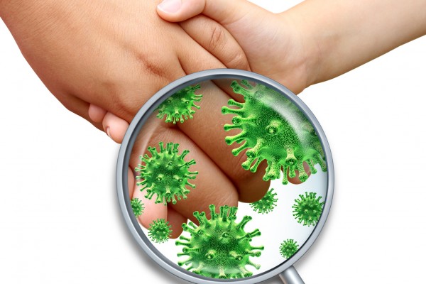 Contagious virus infection with children hands holding and touching spreading dangerous infectious germs and bacteria with a magnifying glass close up on a white background.