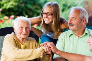 Elderly woman welcoming her family - son and granddaughter in the garden of the nursing home.