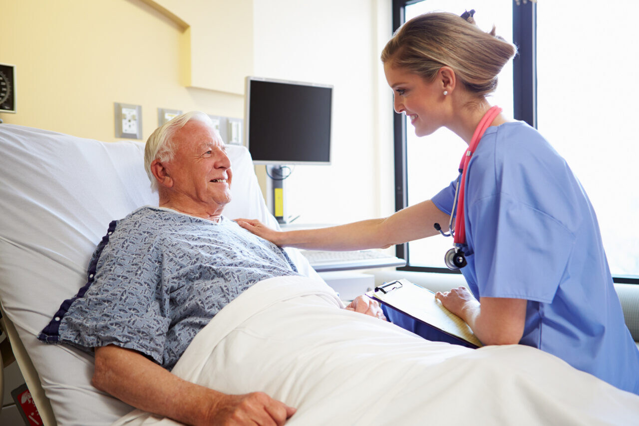 Nurse Talking To Senior Male Patient In Hospital Room