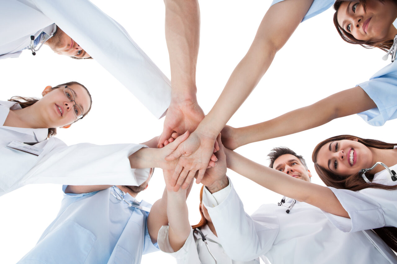 Doctors and nurses stacking hands. Isolated on white