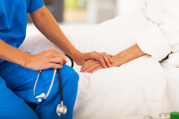medical doctor holing senior patient's hands and comforting her